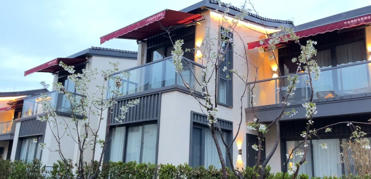 2022杭州亚运度假村2-12地块别墅客房区室外伸缩雨棚安装完成近景:千岛湖郝力克酒店别墅二层外沿一字排开红色伸缩雨篷,铝合金骨架与篷布张紧到位